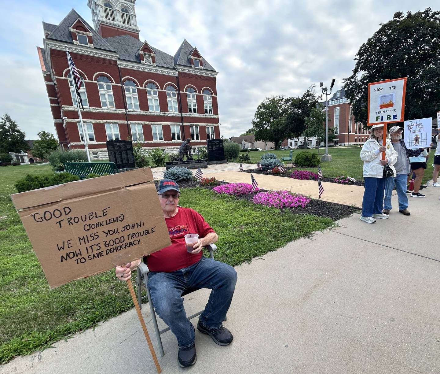 A man holds a sign during Indivisible of Oregon's "Good Trouble Lives On" rally around the Ogle County courthouse in downtown Oregon on Thursday, July 17, 2025. The event was the fifth held to protest ongoing policies and executive orders by President Trump and his administration.