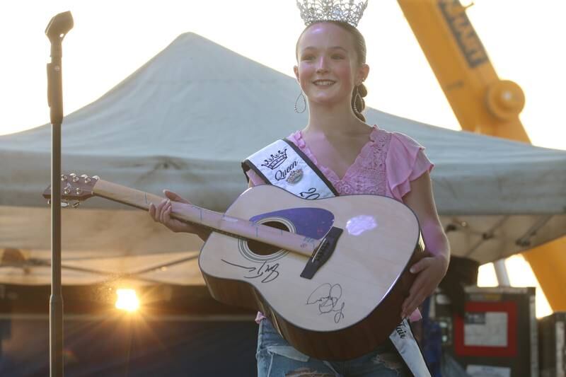 Bureau County Fair queen Kelsey Mongan holds an autograph guitar signed by Josh Turner and Sara Evans on Thursday, Aug. 24, 2023 at the Bureau County Fair in Princeton. The guitar was auctioned off before the concert.