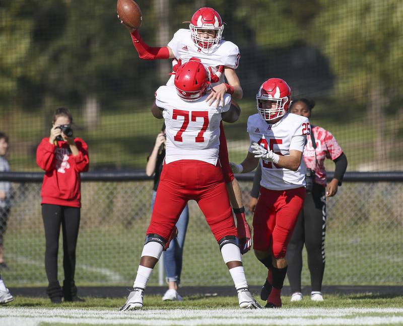 Hinsdale Central’s Mark Skokna (3) is hoisted up by Kiran Amegadjie (77) after scoring a touchdown against Glenbard West in Glen Ellyn.