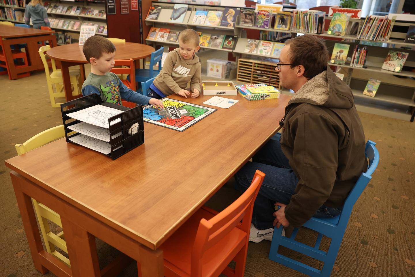 Tyler Petty, right to left, plays a board game with his sons Colby, 4, and Crosby, 5, at the Joliet Public Library Black Road Branch on Monday, Jan. 6, 2025 in Joliet.