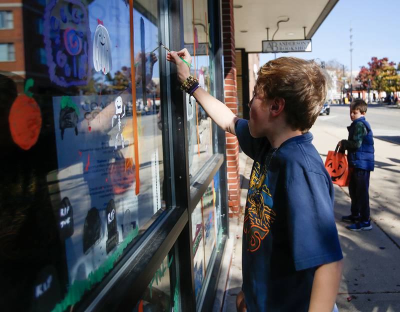 Jonah Davis, 12, of Downers Grove paints the windows of Anderson’s Book Shop in Downers Grove, Ill. on Saturday, October 22, 2022.
