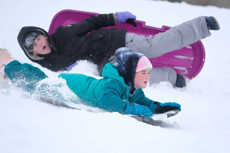 Grace Pullman, 10, wipes out as her friend Grace Kelly, 8, slides past at  Mayor Art Schultz Park. Thursday, Feb. 3, 2022, in Joliet.