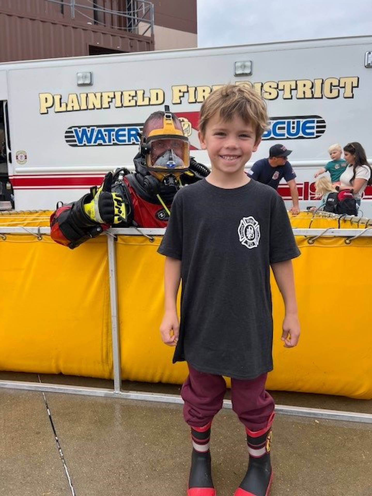 A young visitor poses with a member of the water rescue team  in his scuba gear at the Plainfield Fire Protection District on Saturday, Sept. 16, 2023.