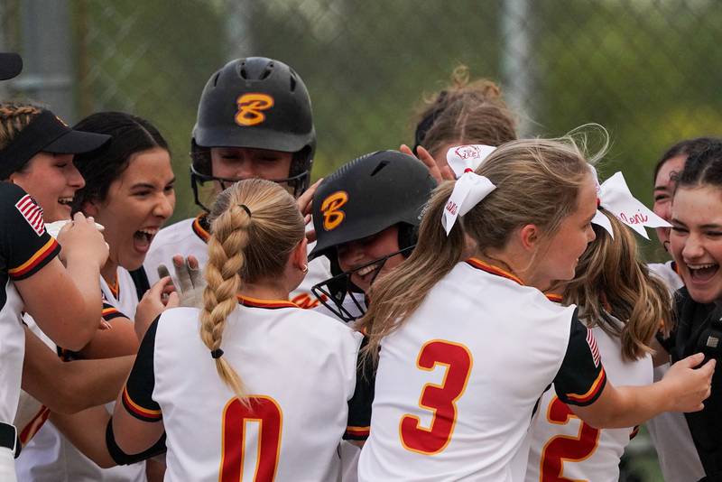 Batavia players surround Bella Zagotta (center) after she crosses the play after hitting a homer against Geneva during a softball game at Batavia High School on Wednesday, May 8, 2024.