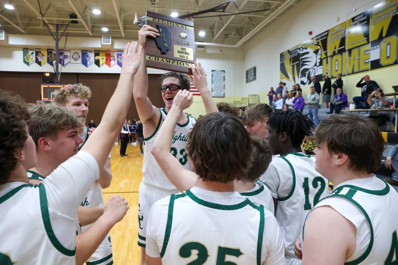 Bishop McNamara's Callaghan O'Connor hoists the IHSA Class 2A Herscher Regional championship plaque as the team celebrates the Fightin' Irish's 66-52 victory over El Paso-Gridley on Friday, Feb. 27, 2026.