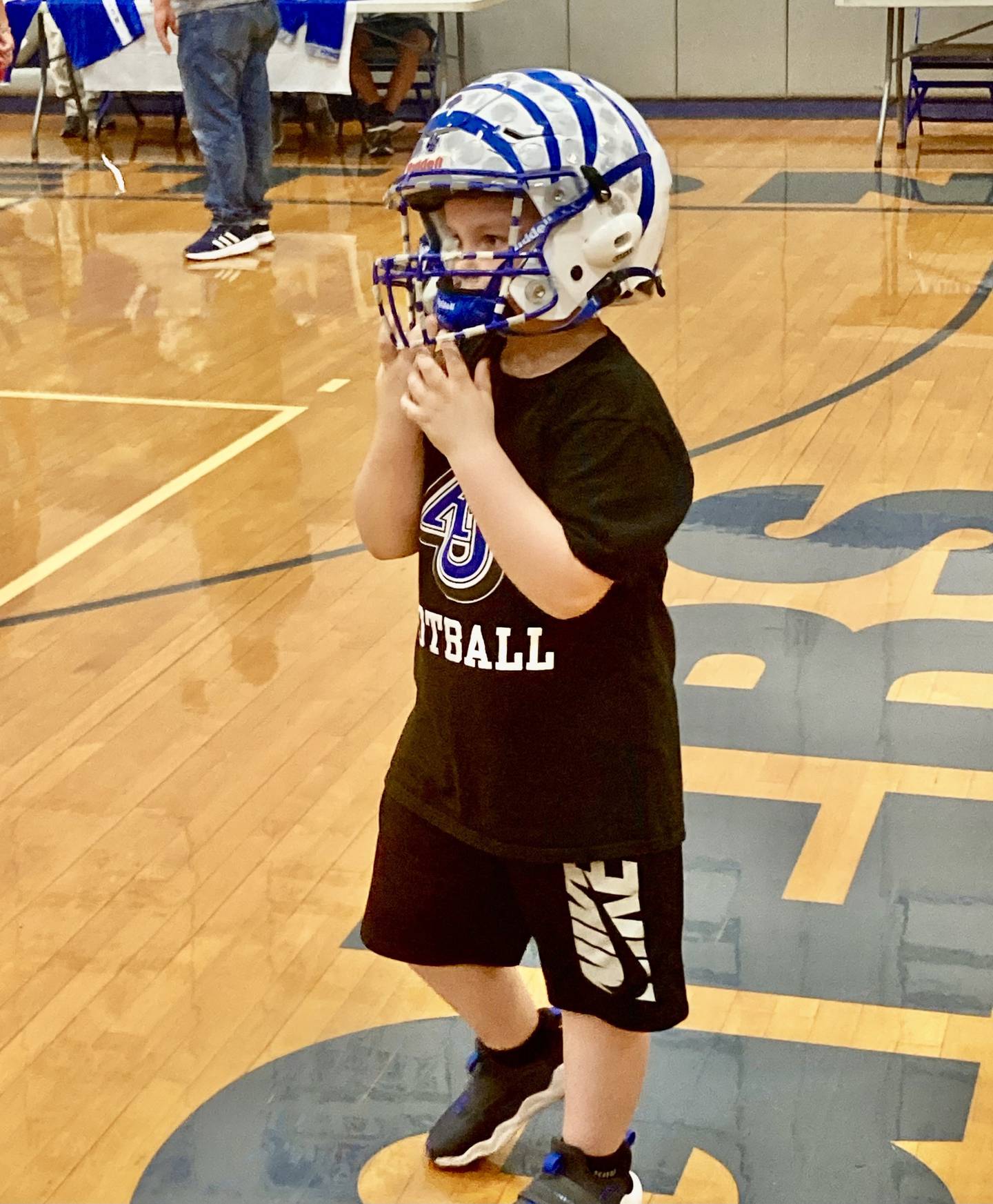 Roman Pearson tries on his brother's helmet during Tuesday's college signing night at Princeton High School. Rhett Pearson will be playing football for Aurora University.