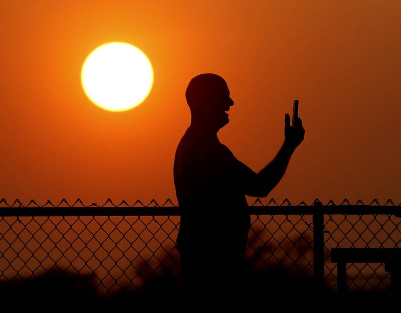 A spectator cheers as he records the 800 meter run during the IHSA Class 3A Huntley Girls Track Sectional Wednesday,  May 11, 2022, at Huntley High School.