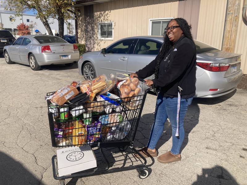A woman leaves the DuPage Township Food Pantry with a cart full of groceries and a donated clock. 
Friday, Oct. 30, 2025.
