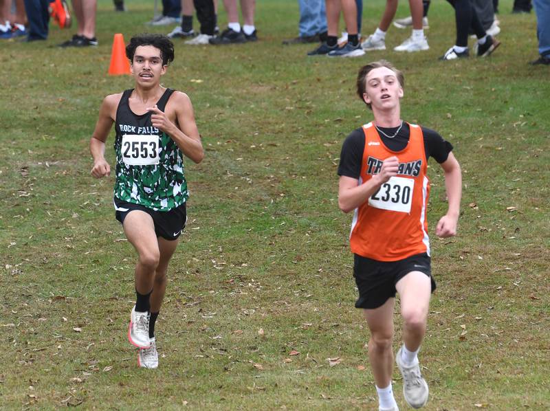 Rock Falls' Ian Finney chases Elmwood's Kai Nelson to the finish line at the Amboy Columbus Day Cross Country Invitational held at Shady Oaks Country Club near Amboy on Monday, Oct. 13, 2025. Finney finished 22nd,