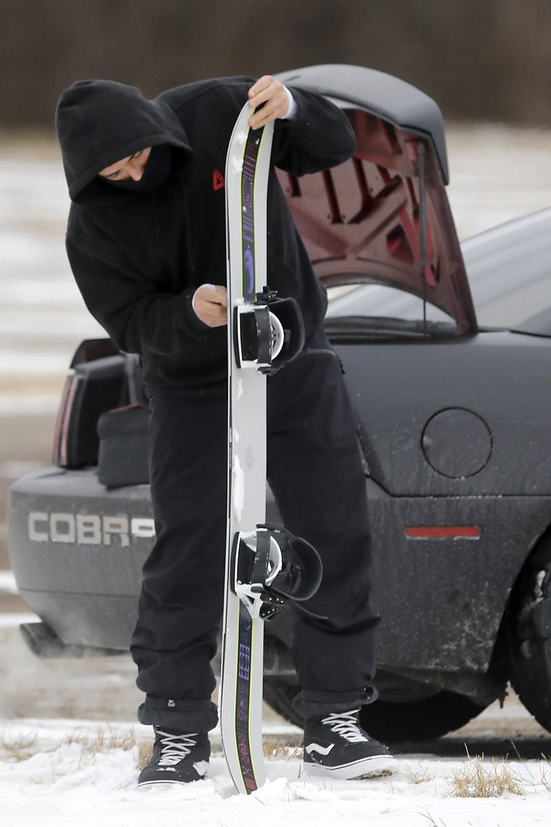 Pablo Nabarro prepares his snowboard before snowboarding at Wilmot Mountain Ski Resort on Thursday, Jan. 16, 2025, in Wilmot, Wisconsin.