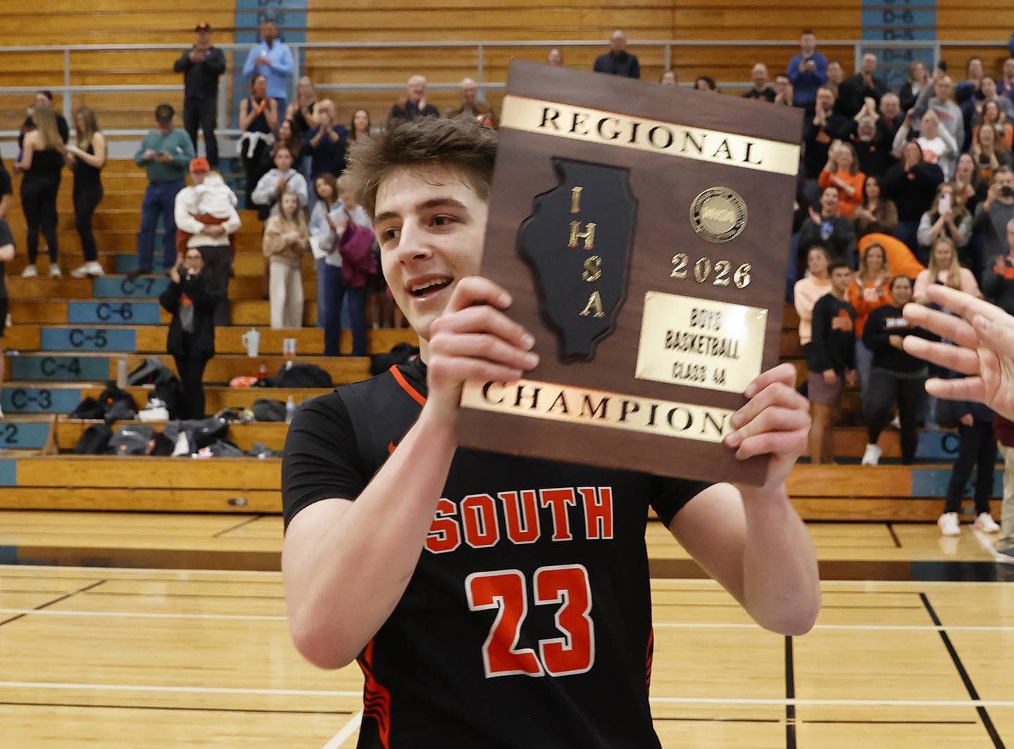 Wheaton Warrenville South's David Showman (23) holds the championship plaque after winning the IHSA boys class 4A Willowbrook regional final between Wheaton Warrenville South and Batavia on Friday, Feb. 27, 2026 in Villa Park, IL.