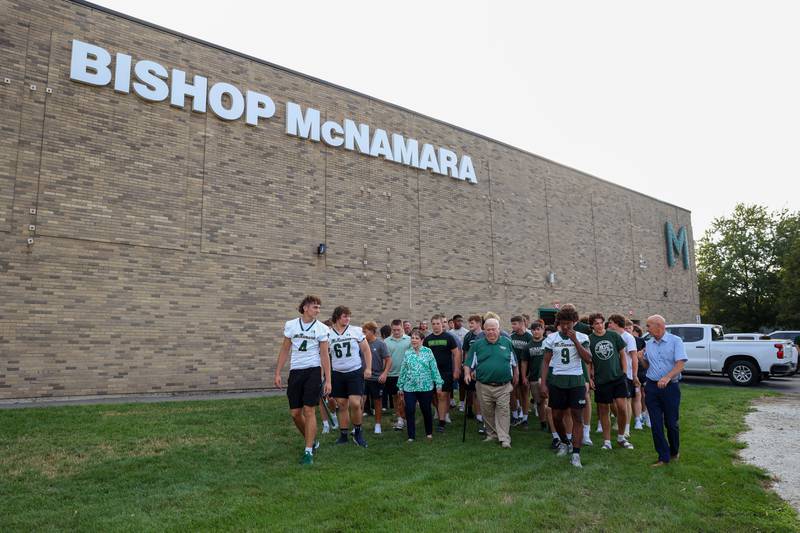 Longtime head football coach Rich Zinanni, center, leads the way to Bishop McNamara's new Rich Zinanni Athletic Complex for the ribbon-cutting ceremony on Thursday, Aug. 21, 2025.