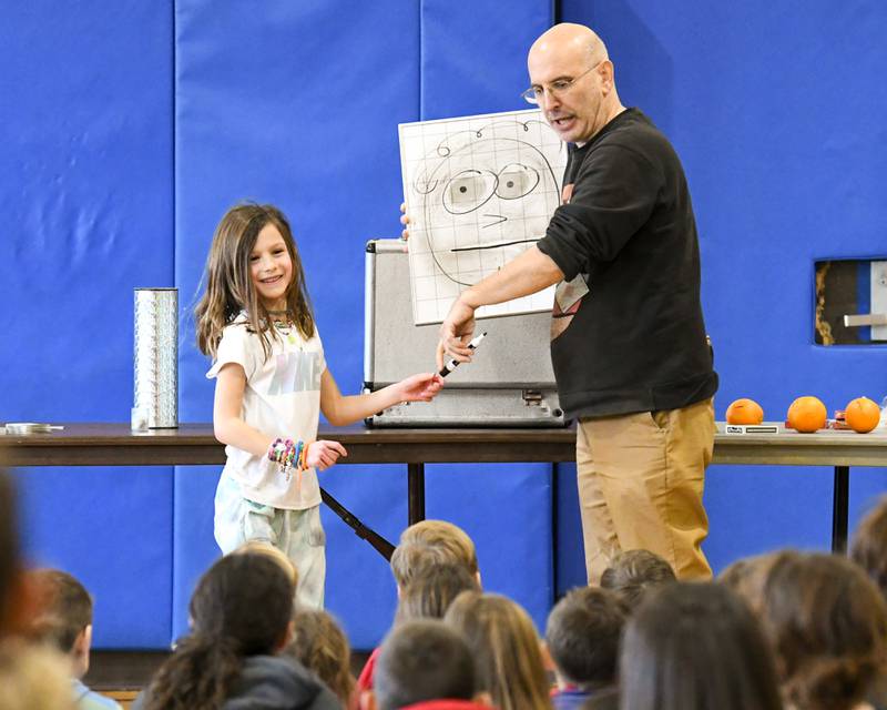 Lucy Della Polla, 7, of Glen Ellyn helps draw a face during the Magic of Gary Kantor magic show on Monday Feb. 19, 2024, held at the Main Street Recreation Center in Glen Ellyn.