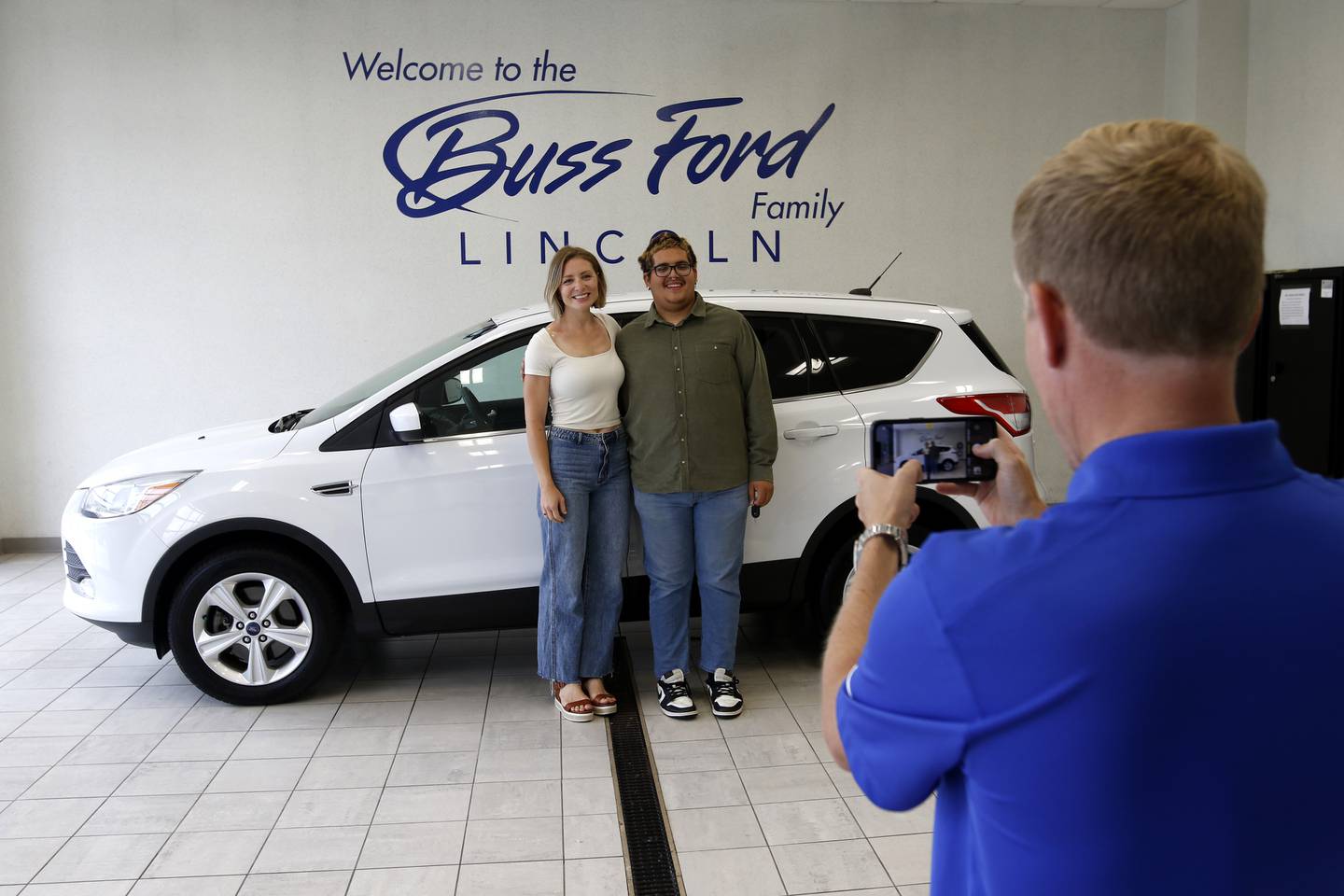 Drew Buss of Buss Ford photographs Kate Knaack and Daniel Avila with his car on Wednesday, June 18, 2025, in McHenry. Avila''s teacher, Knaack, created a GoFundMe to help the 2025 McHenry High School graduate buy a car, allowing him to go to McHenry County College this fall, work this summer, and help his dad care for his 8-year-old twin brothers following his mother's death in February 2024.