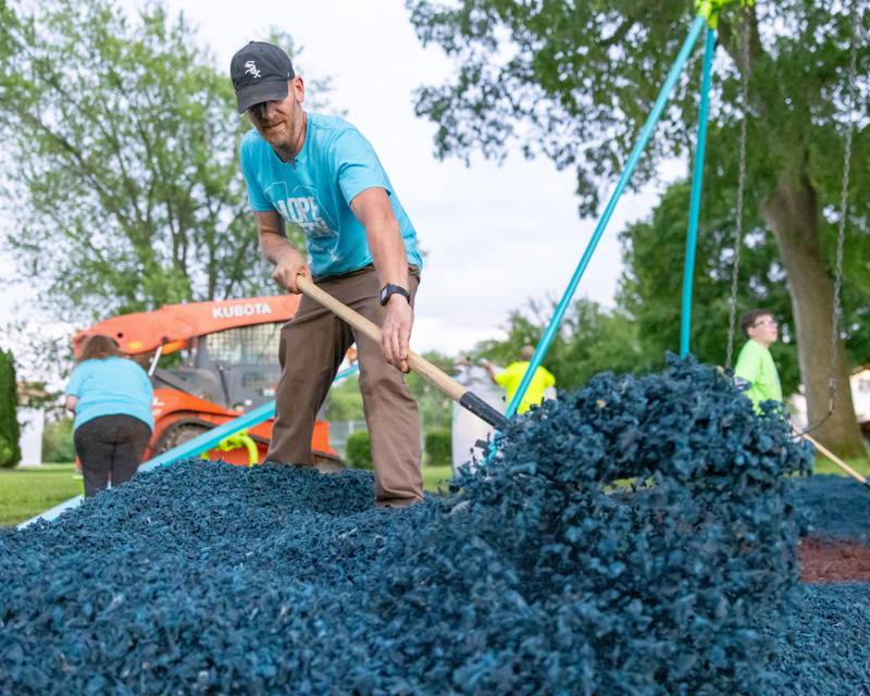 Dominic Parnell spreads out blue rubber mulch across the playground at Grand Ridge Park on June 4, 2025 in Grand Ridge.
