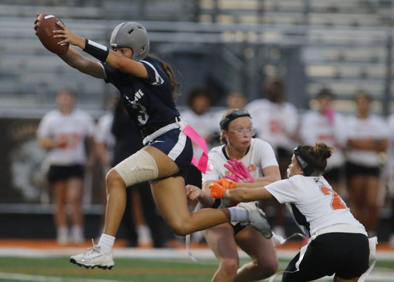 Cary-Grove's Kennedy Manning jumps between Harlem’s Hailey Murath and Ava Fitzsimmons during an IHSA McHenry Sectional semifinal girls flag football game on Monday, Oct. 13, 2025, at McCracken Field in McHenry.