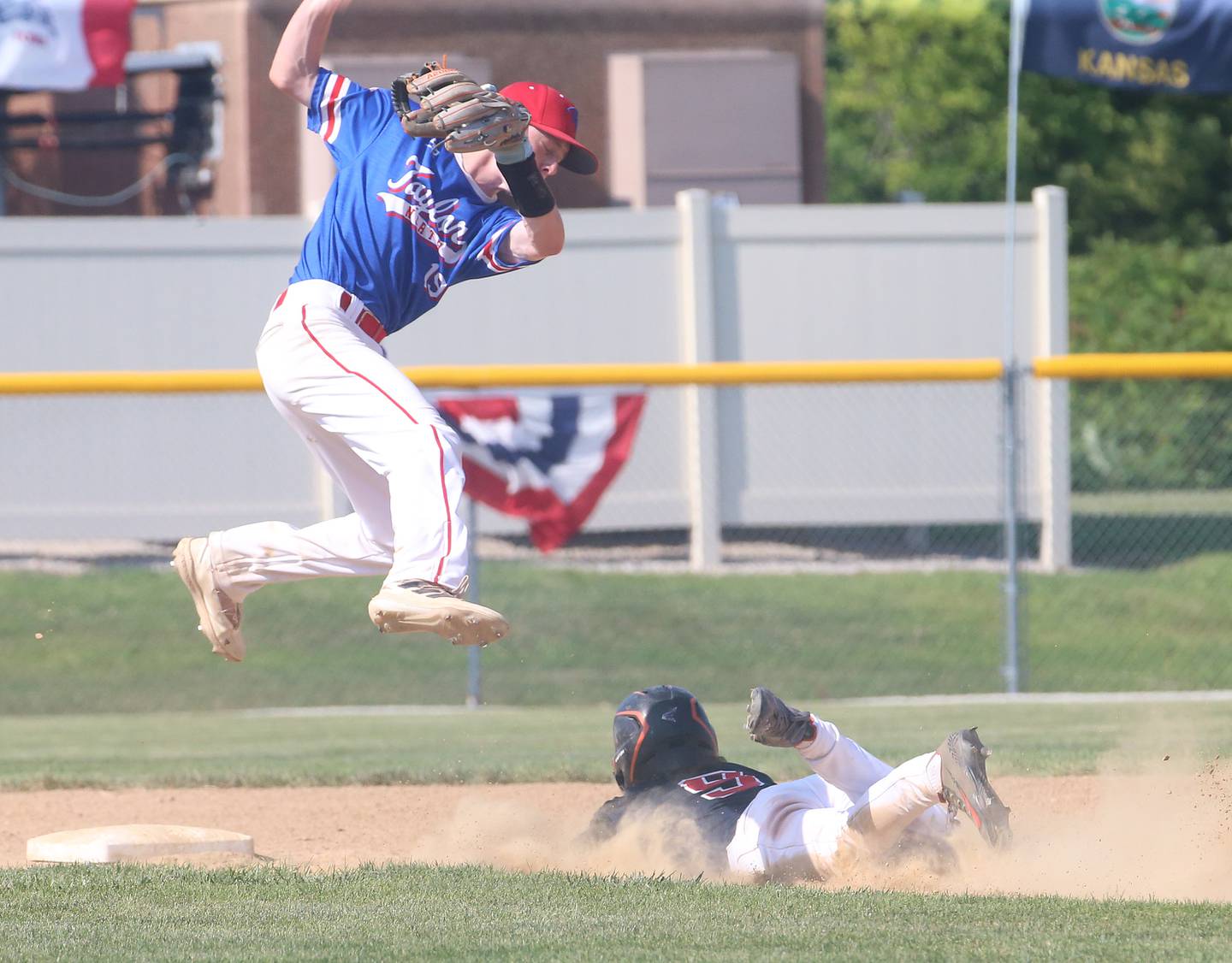 Michigan Taylor North's Seth Anderson leaps in the air as Burbank's Noah Escobedo slides into second base during the Central Regional Senior League championship game on Wednesday, July 26, 2023 at Washington Park in Peru.