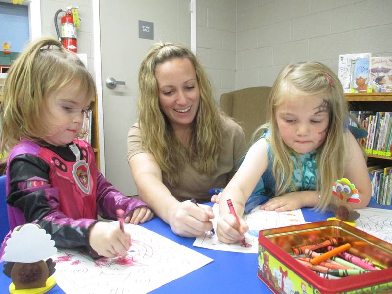 Ashley Hartman helps daughters Audrey, 2, left, and Vivian, 5, color their drawings during an Oct. 22, 2022 open house at the Charles B. Phillips Public Library, which has recently expanded.
