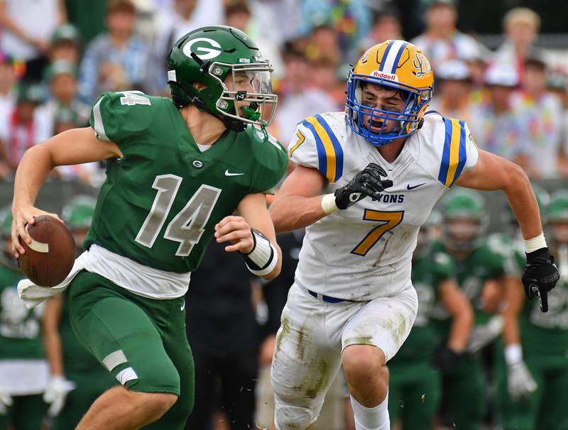Glenbard West quarterback Charlie Cline (14) scrambles as Lyons Township's Jack McQueeney (7) chases during a game on Sep. 16, 2023 at Glenbard West High School in Glen Ellyn.
