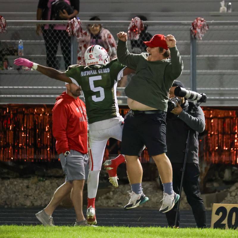 Streator fullback Tristan Finley (5) celebrates his third-quarter touchdown run with assistant coach Austin Schroeder on the Bulldogs' sideline Friday, Oct. 4, 2024, at Doug Dieken Stadium in Streator.