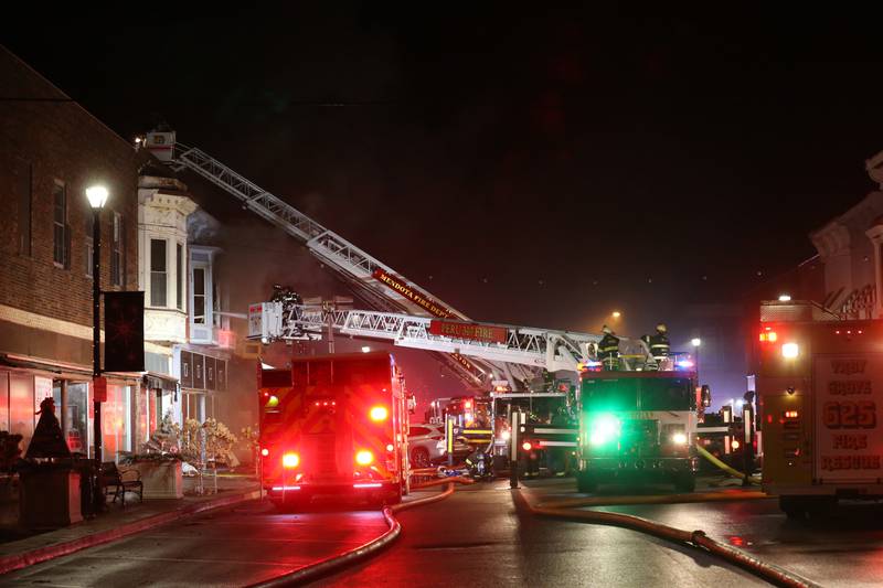 Firefighters use aerial ladder trucks to spray down flames at 708 Illinois Avenue on Friday, Dec. 30, 2022 downtown Mendota.