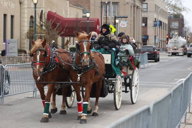 A group takes a horse drawn carriage ride down North Ottawa Street at the Joliet Light Up the Lights Holiday Festival on Friday, Nov. 29, 2024.