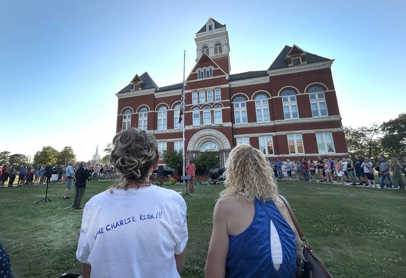 Two women, one wearing a "We Are Charlie Kirk" shirt, attend a candlelight vigil for Charlie Kirk in front of the historic Ogle County Courthouse in downtown Oregon on Sunday, Sept. 14, 2025. An estimated crowd of 350 attended the hour-long evening event.