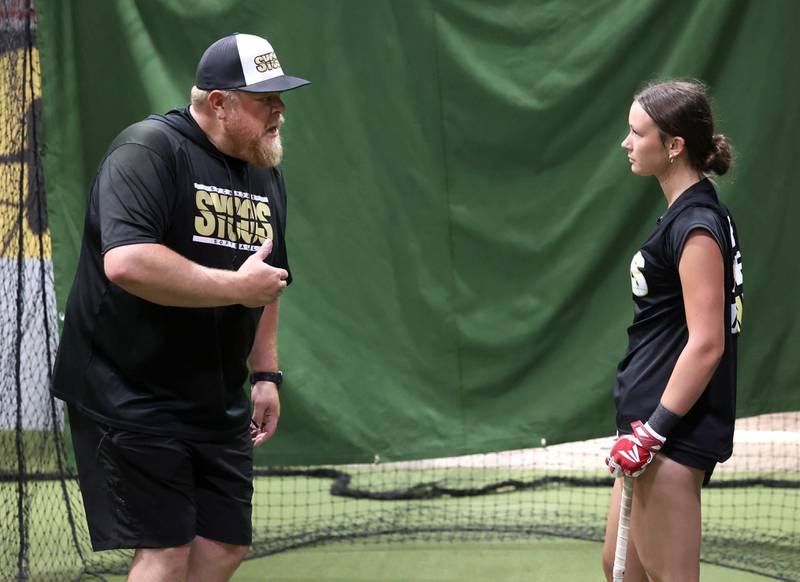 Sycamore Sycos 16u softball coach Ryan Knox gives some swing pointers to Kendall Wolf Wednesday, June 18, 2025, in the batting cage at their indoor practice facility in DeKalb.