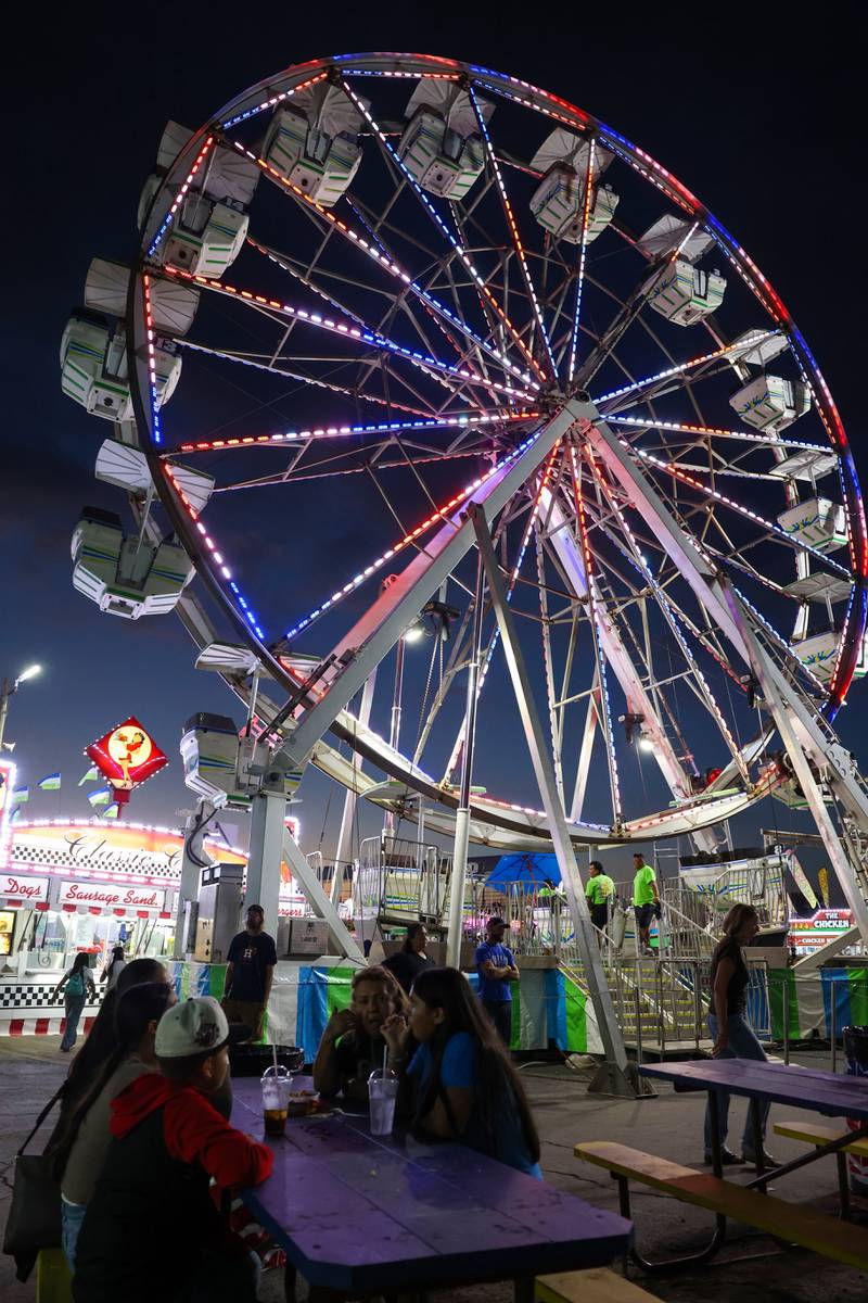 Fairgoers enjoy their food beneath the ferris wheel during the Will County Fair on Aug. 21, 2025.