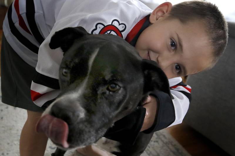 Alex Moscrip, 7, son of Brad and Aleksandra, with his dog, Bubba, on Wednesday. Nov 13, 2024 at his home in McHenry Township. Hewas hit by a car in July and left with traumatic brain injury and is now recovering at home.