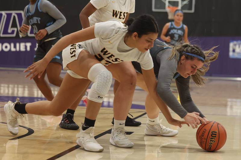 Joliet West’s Miranda Rosales and Joliet Catholic’s Faith Pietras dive for the loose ball in the WJOL Basketball Tournament at Joliet Junior College Event Center on Monday