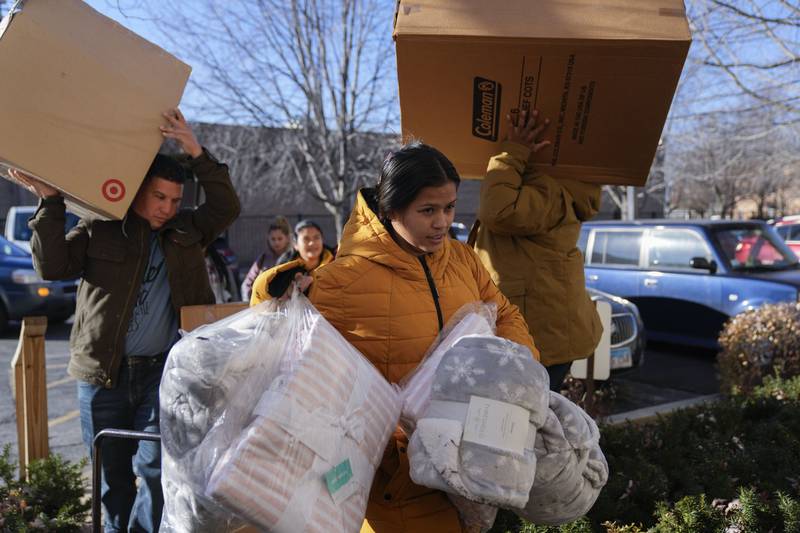 Carolina Gonzalez of Venezuala carries supplies into the Chicago City Life Center Wednesday, Nov. 29, 2023, in Chicago. The community center and church welcomed about 40 migrants who were previously living at police stations and airports.