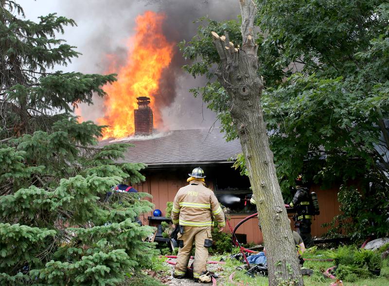 Flames pour out of the roof of a home in the 500 block of North 2782nd Road on Monday, July 21, 2025 in La Salle. FIre departments from Utica, Wallace, Naplate, Spring Valley, Mendota, Troy Grove, La Salle, Peru, Oglesby and Tonica responded to the scene. Fire crews were dispatched at 9:45 a.m. La Salle Police and La Salle County Sheriff were also on the scene.