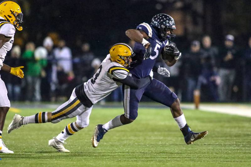 IC Catholic Prep's Aaron Harvey (5) runs away from St Laurence's Corey Taubr (3) during Class 4A third round playoff football game between St Laurence at IC Catholic Prep.  Nov 11, 2023.