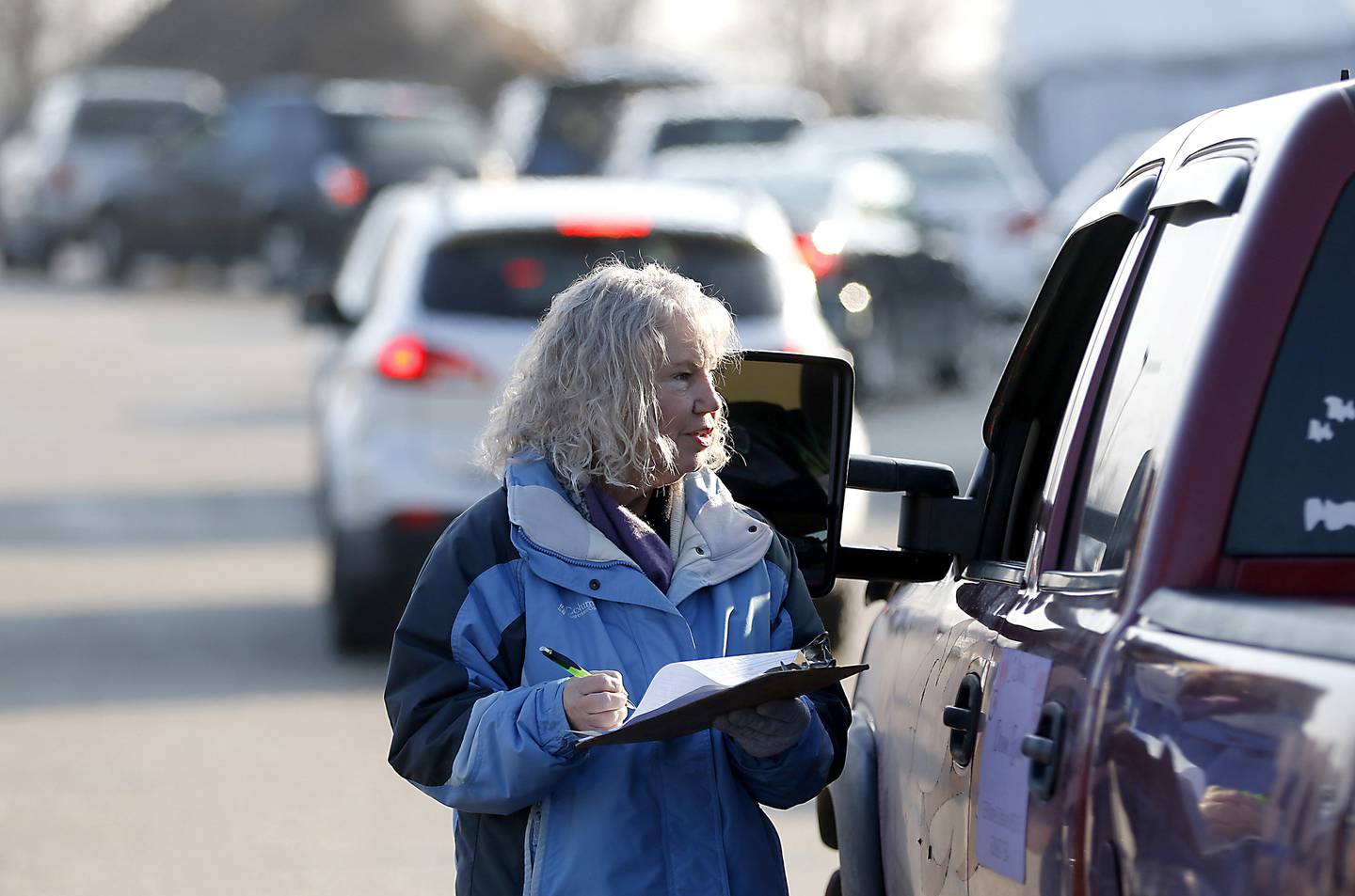 Volunteer Cindy Wiers collects information from a recipient as people wait in line Tuesday, Jan. 10, 2023, at the FISH of McHenry Food Pantry, 3515 N. Richmond Road in Johnsburg, to receive food. The pantry, which has changed how it distributes food since the COVID-19 pandemic, is now raising $150,000 to add more storage and a heated garage onto the building.