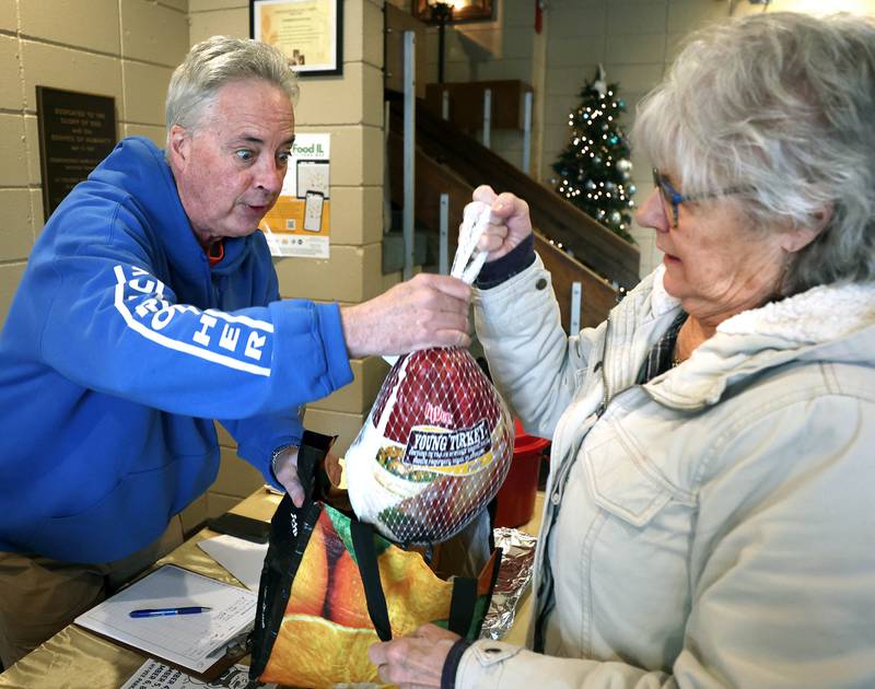 Cheryl Johnson, from Cortland, hands her turkey donation to TD Ryan, host of the TD Ryan Unleashed podcast, during Ryan’s Let’s Talk Turkey Thanksgiving food drive Friday, Nov. 21, 2025, at the Salvation Army food pantry in DeKalb.