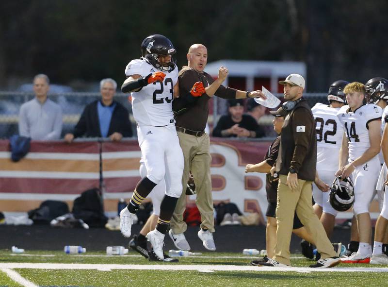 Joliet Catholic's head coach Jake Jaworski congratulates Jordan Anderson (23) after Anderson scored a touchdown during the varsity football game between Joliet Catholic and Brother Rice on Friday, October 8, 2021 at Brother Rice high school in Chicago, IL.