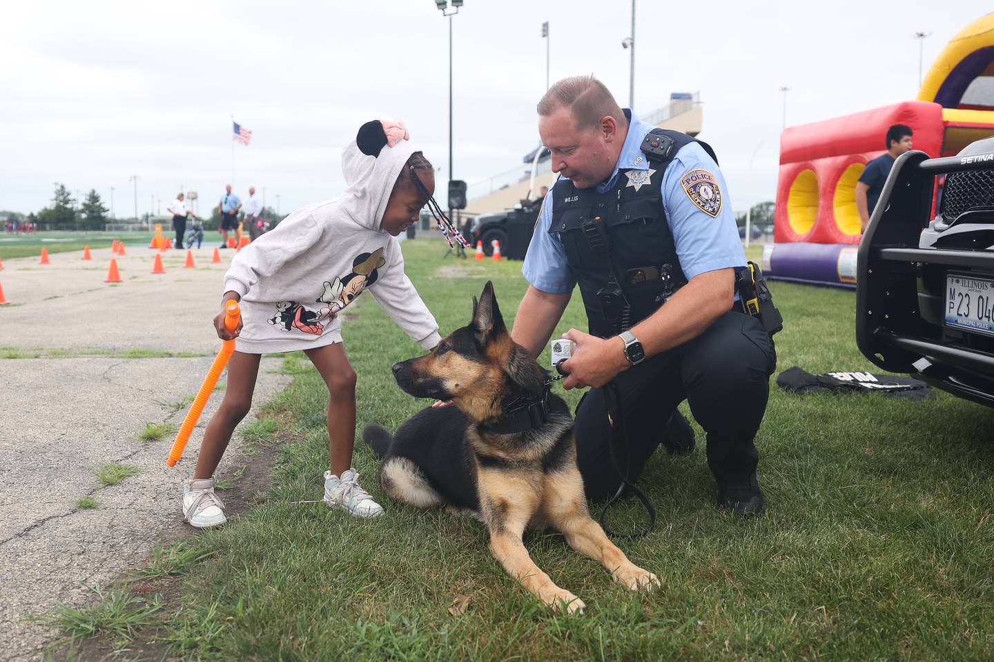 K9 officer Dan Willis watches as Alani Christian, 7, pets Ady at Joliet Police Department’s National Night Out on Tuesday, Aug. 6, 2024.
