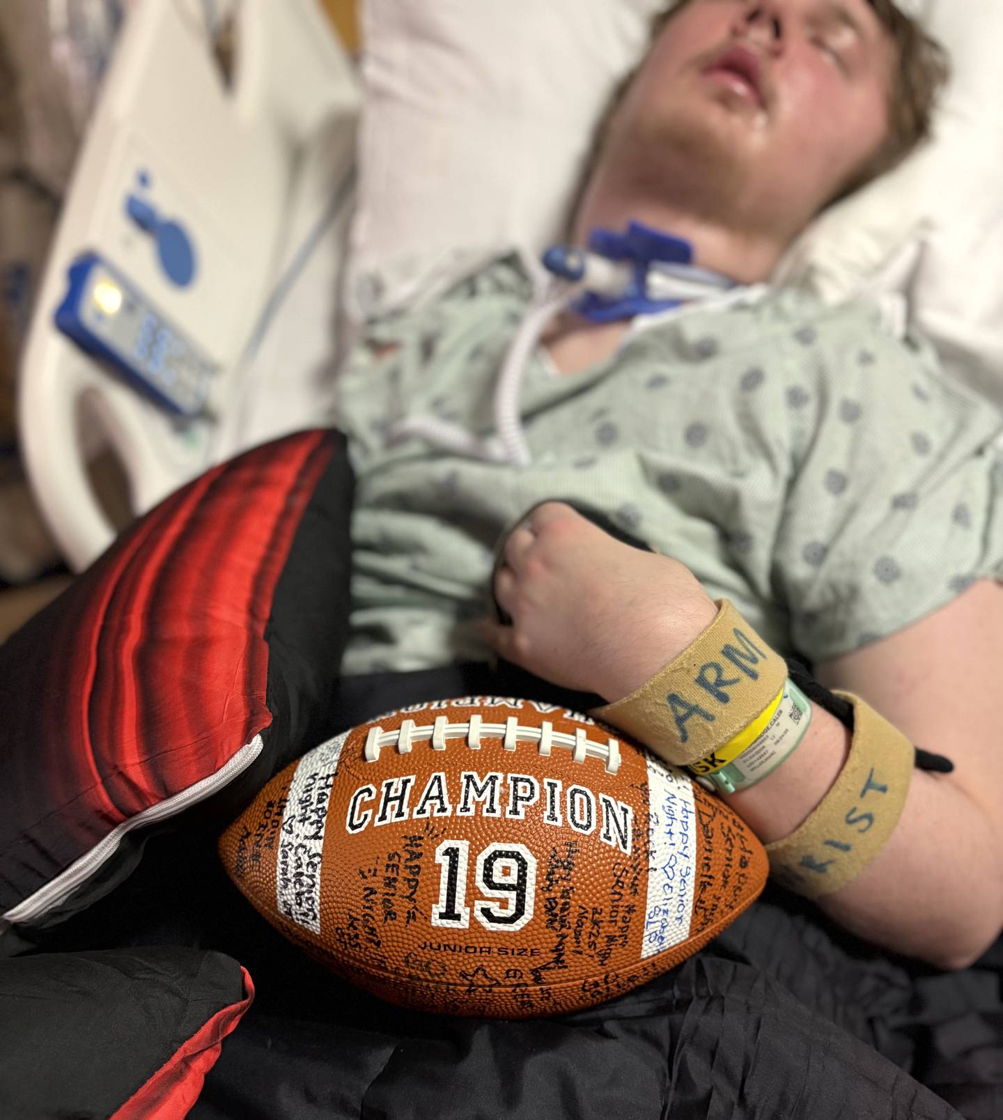 Caleb Outerbridge, now 17, is presented with a signed football to celebrate his senior night from his hospital room in October. Caleb, who suffered a rare autoimmune disease just before last Thanksgiving that rendered him unconscious, has been making progress as he heals from brain injury caused by the disease.