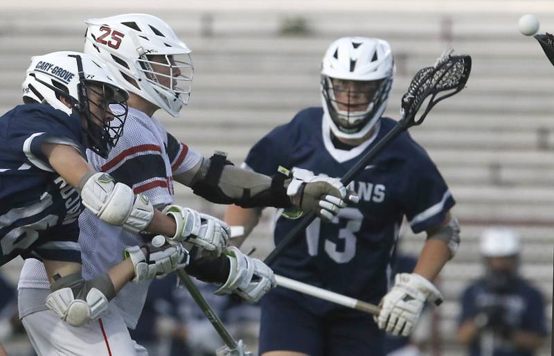 Huntley's Bobby Pupich takes a shot on goal between Cary-Grove's Dylan Tamason (left) and Paul Brock (right) during the Marian Central Sectional boys lacrosse semifinal match on Wednesday, May 28, 2025, at Marian Central High School in Woodstock.
