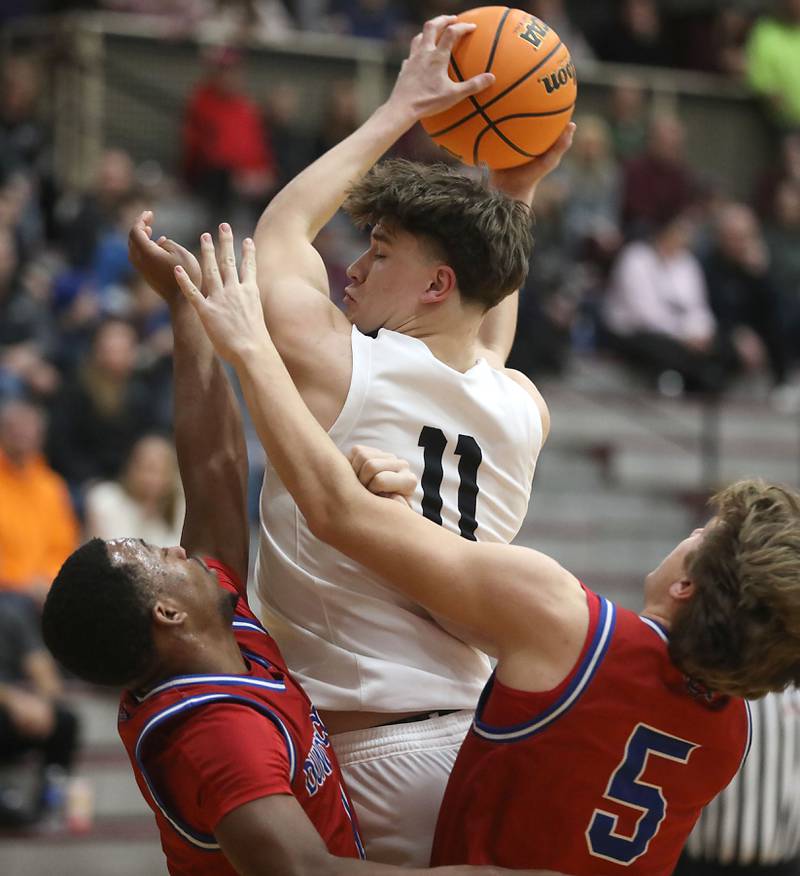 Prairie Ridge's Elijah Loeding tries to pass out of the pressure ofnj Dundee-Crown's Kadin Malone (left) and Max Backus (right) during a Fox Valley Conference boys basketball game on Friday, Jan. 16, 2026, at Prairie Ridge High School in Crystal Lake.