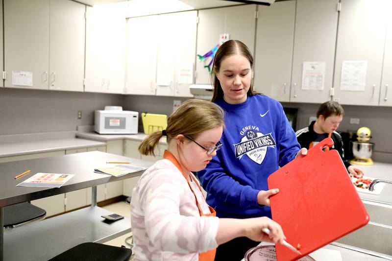 Cailla Swanson, a learning behavior specialist at Geneva High School, works with student Izzy Hauth during a cooking class.