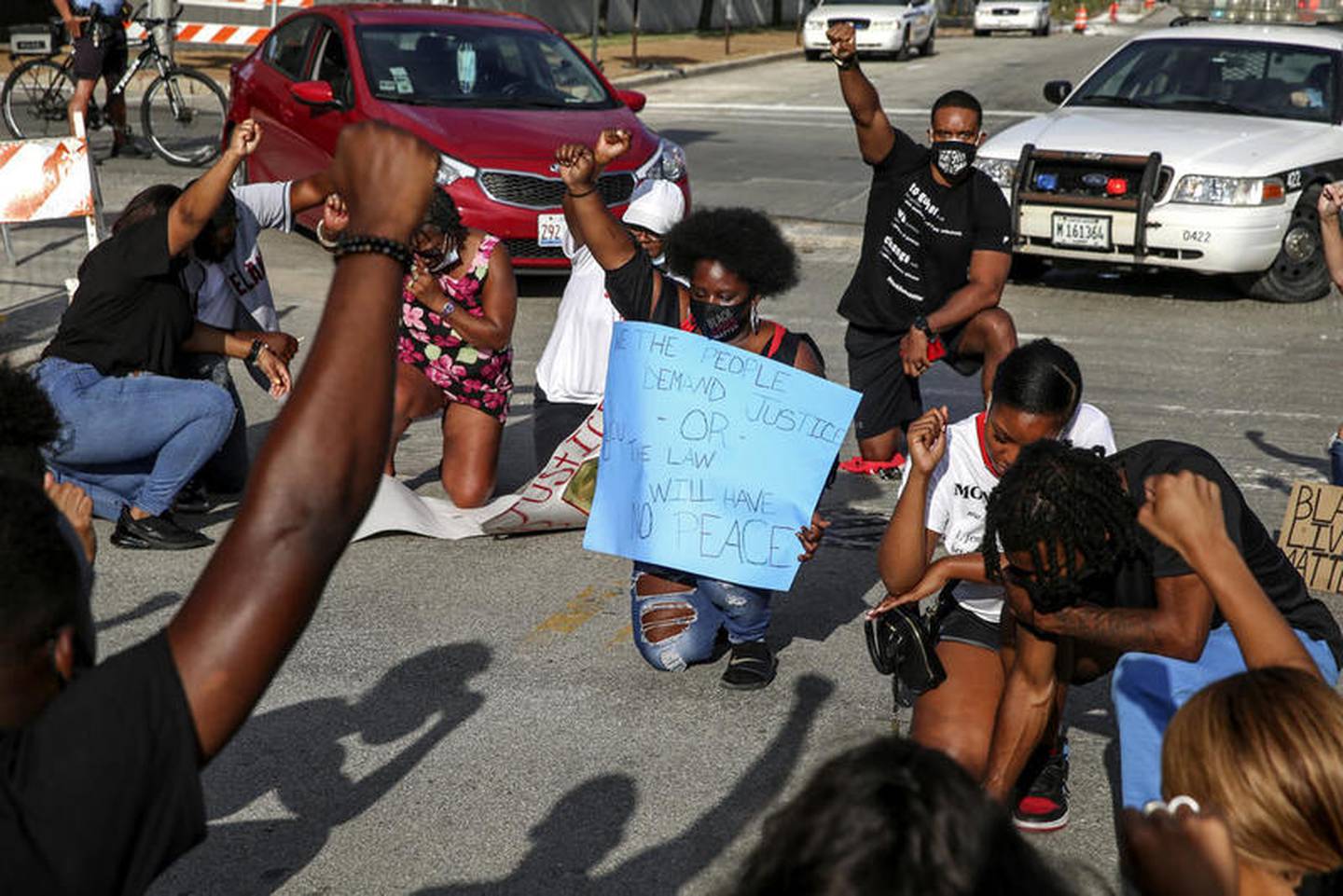 Demonstrators can be seen taking a knee during a moment of silence outside the Will County Courthouse on Saturday, Aug. 22, 2020, in response to the January 28 overdose death of Eric Lurry who died in police custody.