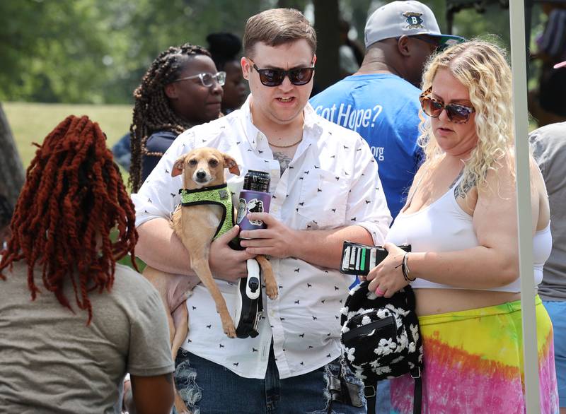 Ethan Daugherty holds Borb the dog as he and Lauren Mitacek drop by the Lifescape tent during the Juneteenth Community Celebration Sunday, June 18, 2023, at Hopkins Park in DeKalb. The event featured vendors, food, music, games, and more.