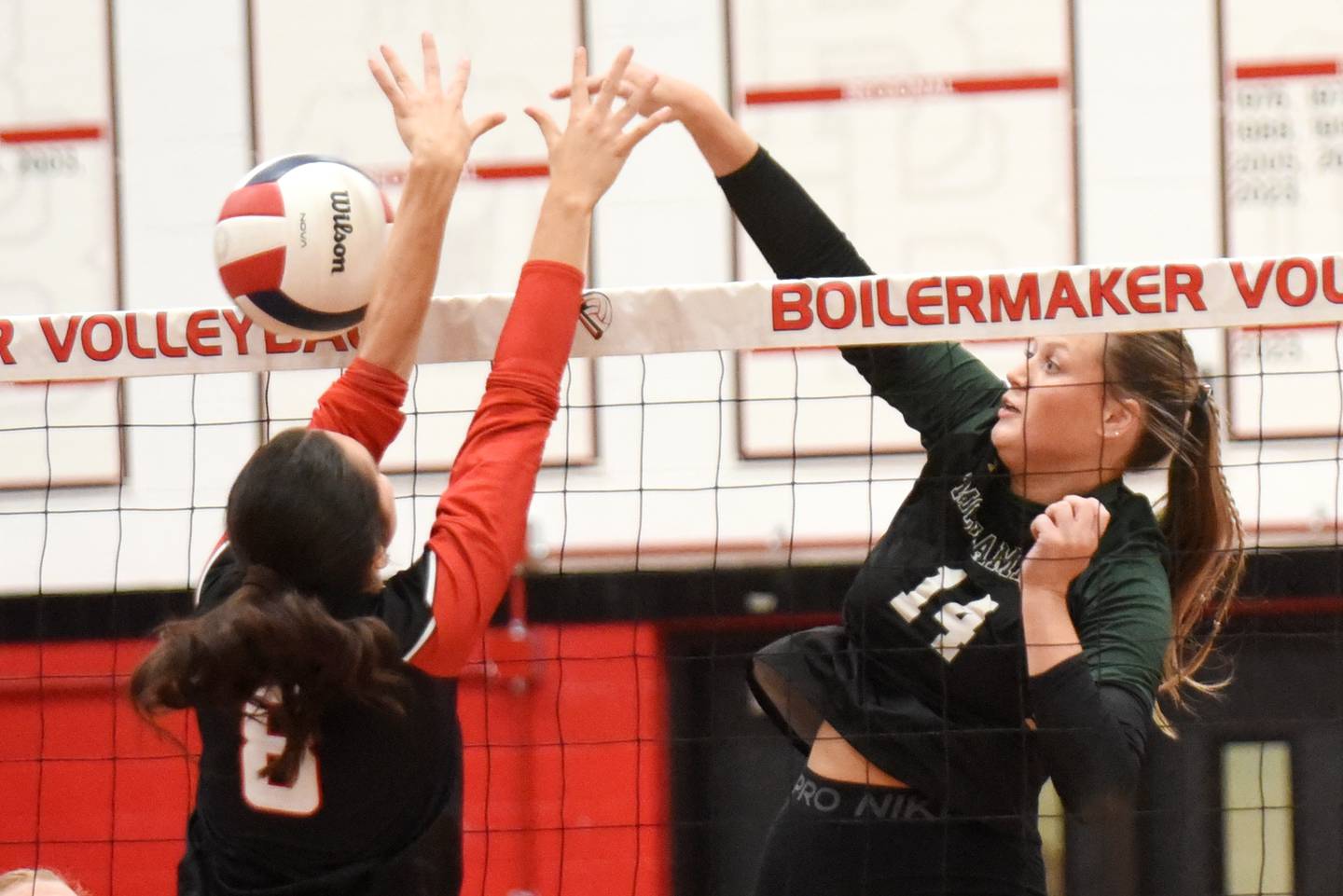 Bishop McNamara's Kate Dole, right, sneaks a hit past Bradley-Bourbonnais' Hannah Wojnowski during All-City action at Bradley-Bourbonnais Wednesday, Sept. 10, 2025.