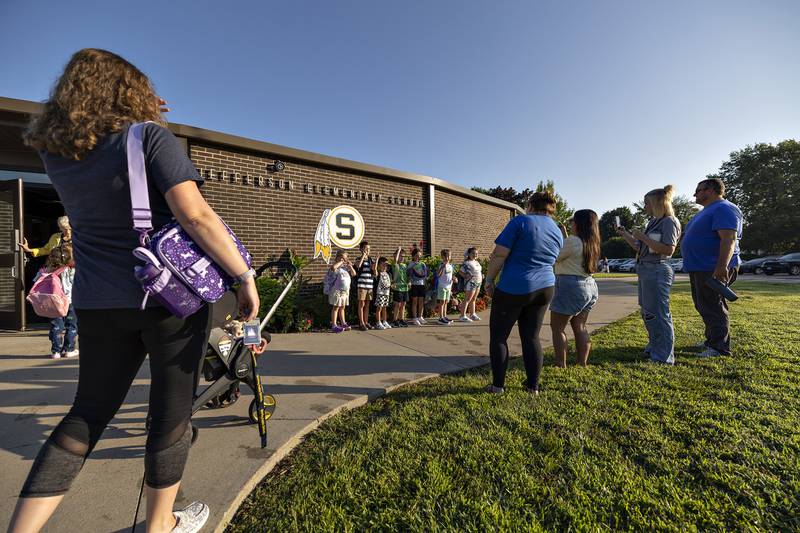 Students hold up their class number as they have their pictures taken Thursday, August 14, 2025, outside of Jefferson School in Sterling.