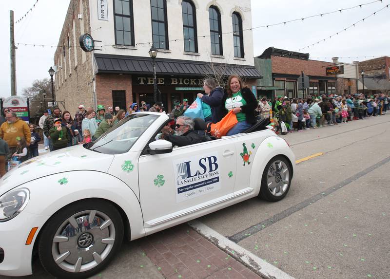 Employees with La Salle State Bank ride in a car during the St. Patrick's Day parade on Saturday, March 15, 2025 downtown Utica.