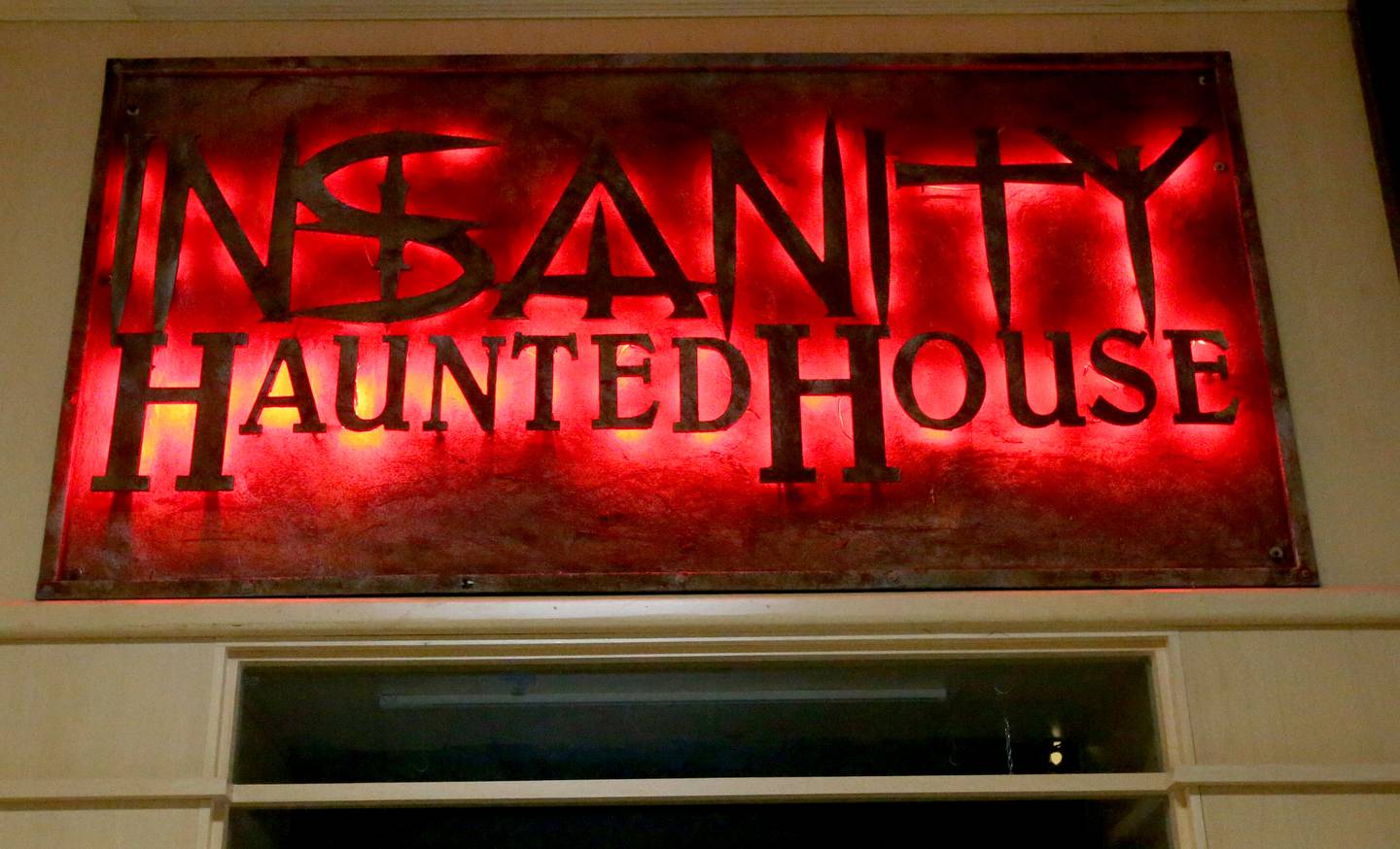 A lighted Insanity Haunted House sign hangs outside the storefront on Thursday, Oct. 3, 2024 at the Peru Mall.  The attraction has been voted the number one haunted house in Illinois in 2022 and 2023. It is open Friday's Saturdays, and Sundays through Nov. 2. There's also a kids matinee on Sundays. For more info visit www.insanityhh.com