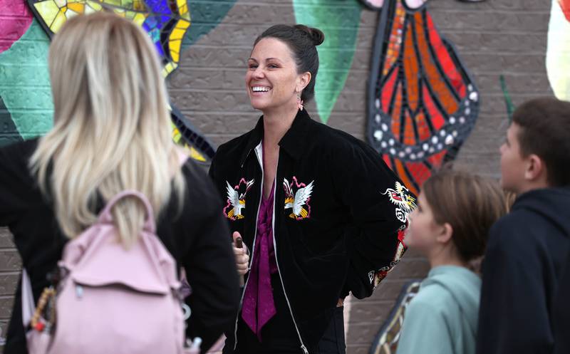 Mural artist Danielle Casali (right) talks to attendees and volunteers Thursday, Oct. 19, 2023, during the unveiling and ribbon cutting of the new City Hall mural. The mural is on the on the south wall of City Hall and was completed with the help of many volunteers who wanted to be a part of the project.
