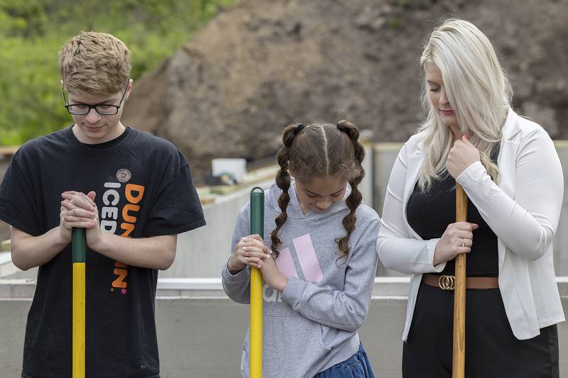 Kayden Carter, 18, Makenna Muhammad, 12, and Megin Steeb bow their heads in prayer Saturday, May 4, 2024 at the blessing of their new Habitat for Humanity home in Dixon.